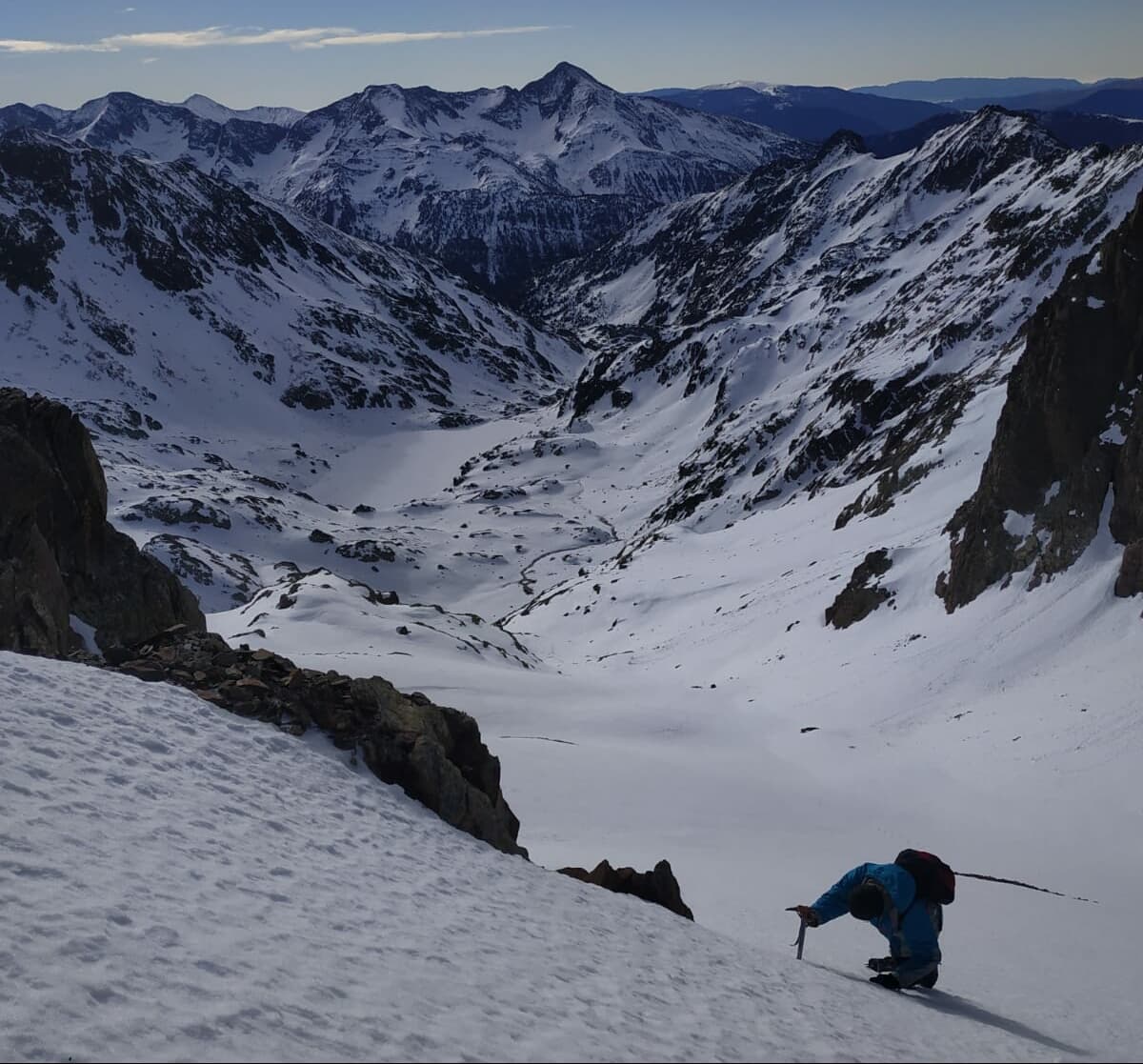 A skier on a steep snow slope in high mountains